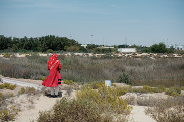 April, 6, 2019: Abu Dhabi, UAE: Female tourist wearing red gown at Al Wathba Wetland Reserve Abu Dhabi, UAE