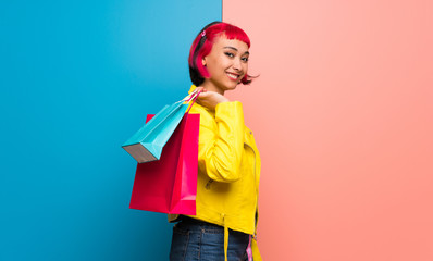 Young woman with yellow jacket holding a lot of shopping bags