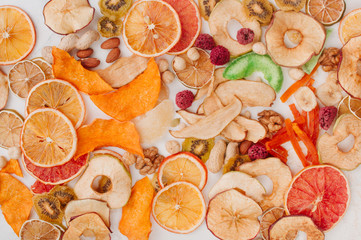 Mixed dried fruit and vegetable chips, candied pumpkin slices, nuts and seeds on white background