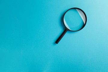 Magnifying glass on blue background. Top view. Flat lay. Copy space. Minimal creative concept. Search concept