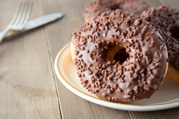 Chocolate donuts breakfast or dessert, wooden table. Close up glazed donuts. Sweet food. Pastry.