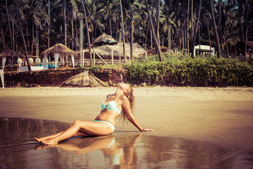 Portrait of a young woman on the beach against the backdrop of palm trees