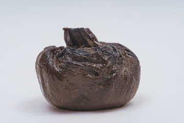 Spoiled mushroom champignon on a white background. Dried black mushroom. Improper preservation of...