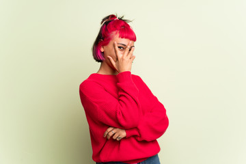 Young woman with red sweater covering eyes by hands and looking through the fingers