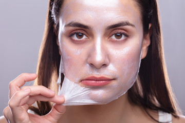 Woman Removing Peeling Mask From Her Face