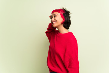 Young woman with red sweater listening to something by putting hand on the ear