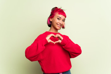 Young woman with red sweater making heart symbol by hands