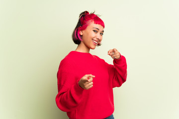 Young woman with red sweater pointing to the front and smiling