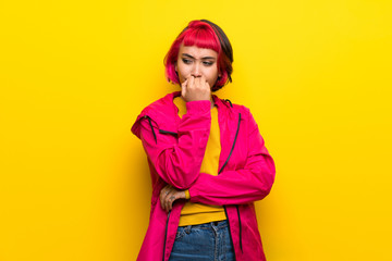 Fototapeta premium Young woman with pink hair over yellow wall having doubts