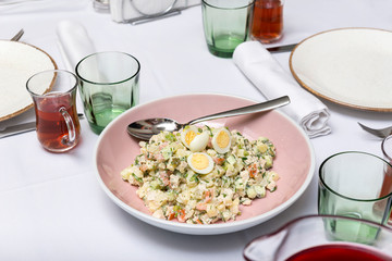 Olivier salad with quail eggs in a plate on the table
