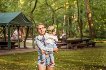 Fototapeta premium Teen girl with baby sister in the Park for a walk.