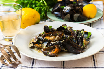 Fototapeta na wymiar Boiled black mussels, lemon, vine, parsley and pliers.