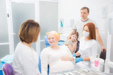 pregnant woman at the reception at the dentist, the husband and daughter are present in the office. Dental treatment for pregnant women