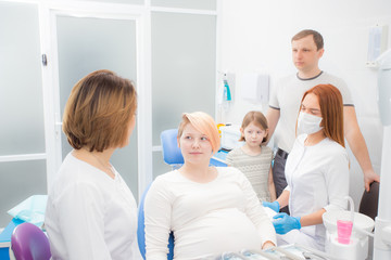 pregnant woman at the reception at the dentist, the husband and daughter are present in the office. Dental treatment for pregnant women