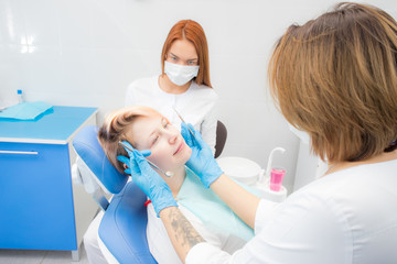 woman in the dentist's chair, the doctor adjusts the patient's head, the dental assistant