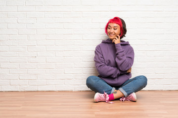 Young woman with pink hair sitting on the floor looking to the side