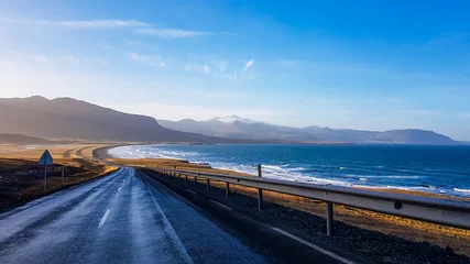 Door stickers Atlantic Ocean Road An endless road along the coast. Road stretches over the horizon. Waves gently wash the shore. Empty road, with no cars pasing by. In the back tall mountains emerge from the seashore. Road trip.