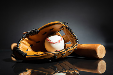 Leather Glove With Baseball And Bat Against Black Background