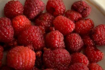 Big ripe raspberries are laying on the  table covered with white tablecloth