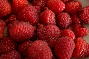 Big ripe raspberries are laying on the  table covered with white tablecloth