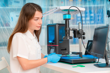 Woman worker in control of Resin LCD / DLP / SLA 3D Printer in technology lab