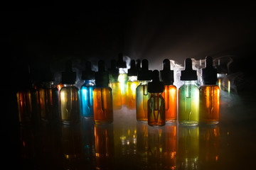 Vape concept. Smoke clouds and vape liquid bottles on dark background. Light effects. Useful as...