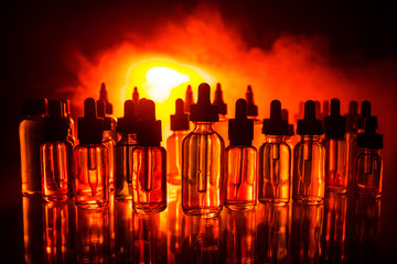 Vape concept. Smoke clouds and vape liquid bottles on dark background. Light effects. Useful as...