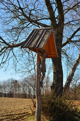 drewniany krzyż przydrożny z dużą figurą Chrystusa pod daszkiem 1