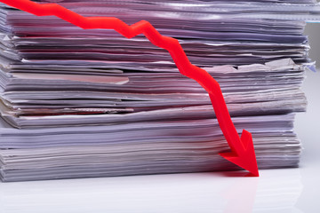 Red Decreasing Graph On Table Against Stack Paper