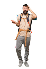 Hiker man surprised and pointing finger to the side over isolated white background