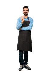 Full-length shot of Man with apron happy and counting four with fingers over isolated white background