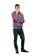 Full-length shot of Handsome man with sweatshirt covering mouth with hands over isolated white background