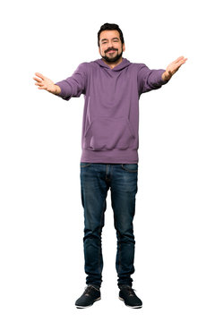 Full-length shot of Handsome man with sweatshirt presenting and inviting to come with hand over isolated white background