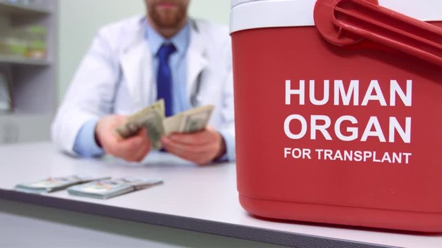 Doctor counts money behind the red organ trafficking container