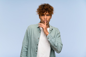 Young african american man over isolated blue wall showing a sign of silence gesture putting finger in mouth