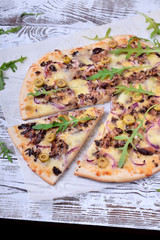 Pizza with fish, cheese and arugula on white wooden table