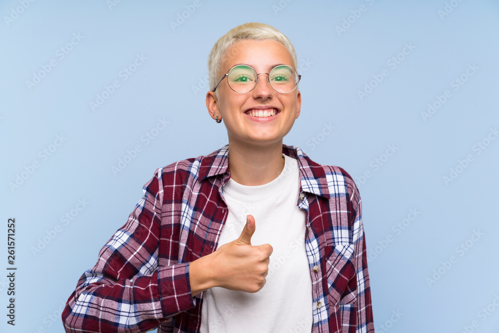 Wall mural teenager girl with white short hair over blue wall giving a thumbs up gesture