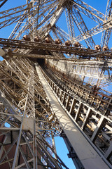Low angle view close up inside structure of Eiffel Tower in clear blue sky day