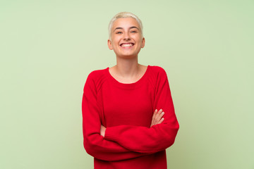 Teenager girl with white short hair over green wall keeping the arms crossed in frontal position