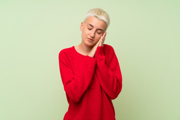 Teenager girl with white short hair over green wall making sleep gesture in dorable expression