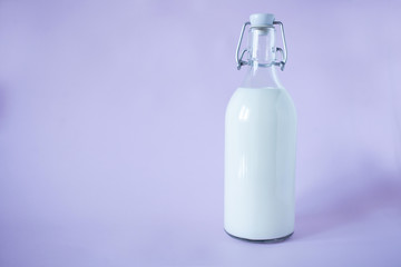 Fresh milk for breakfast in a glass bottle on a lavender background