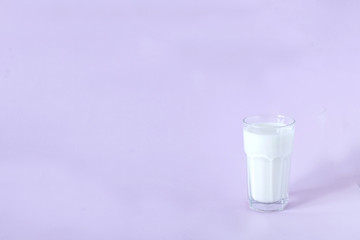 glass of fresh milk on a lavender background