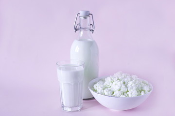 Fresh cottage cheese and milk for breakfast in a glass bottle and a glass of milk in the center of the frame on a lavender background