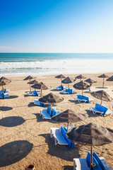 Lounge chairs with sun umbrella on sandy beach