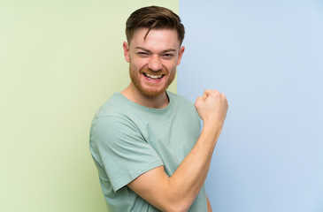 Redhead man over colorful background celebrating a victory