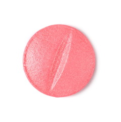 One pink pill macro isolated on white background, top view
