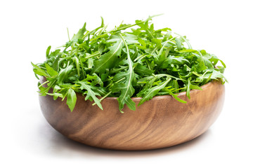 Rocket salad leaves in wooden bowl isolated on white