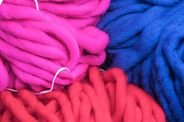primer plano de lanas gruesas de colores rosa azul y rojo