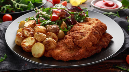 Homemade breaded pork schnitzel with roast potato and vegetables