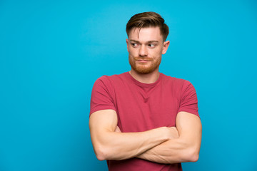 Redhead man on isolated blue wall standing and thinking an idea